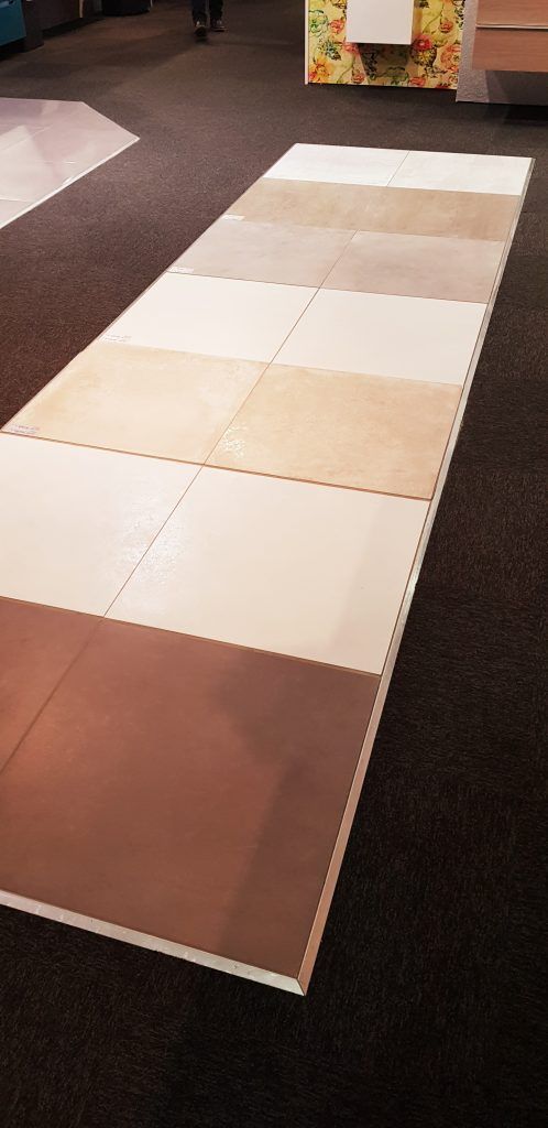 Tapis long à carreaux beiges, blancs et bruns alternés sur un sol recouvert de moquette foncée.