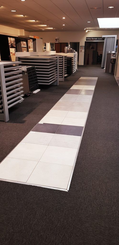 Couloir intérieur avec dalles de sol blanches déroulées et tables empilées le long du côté gauche