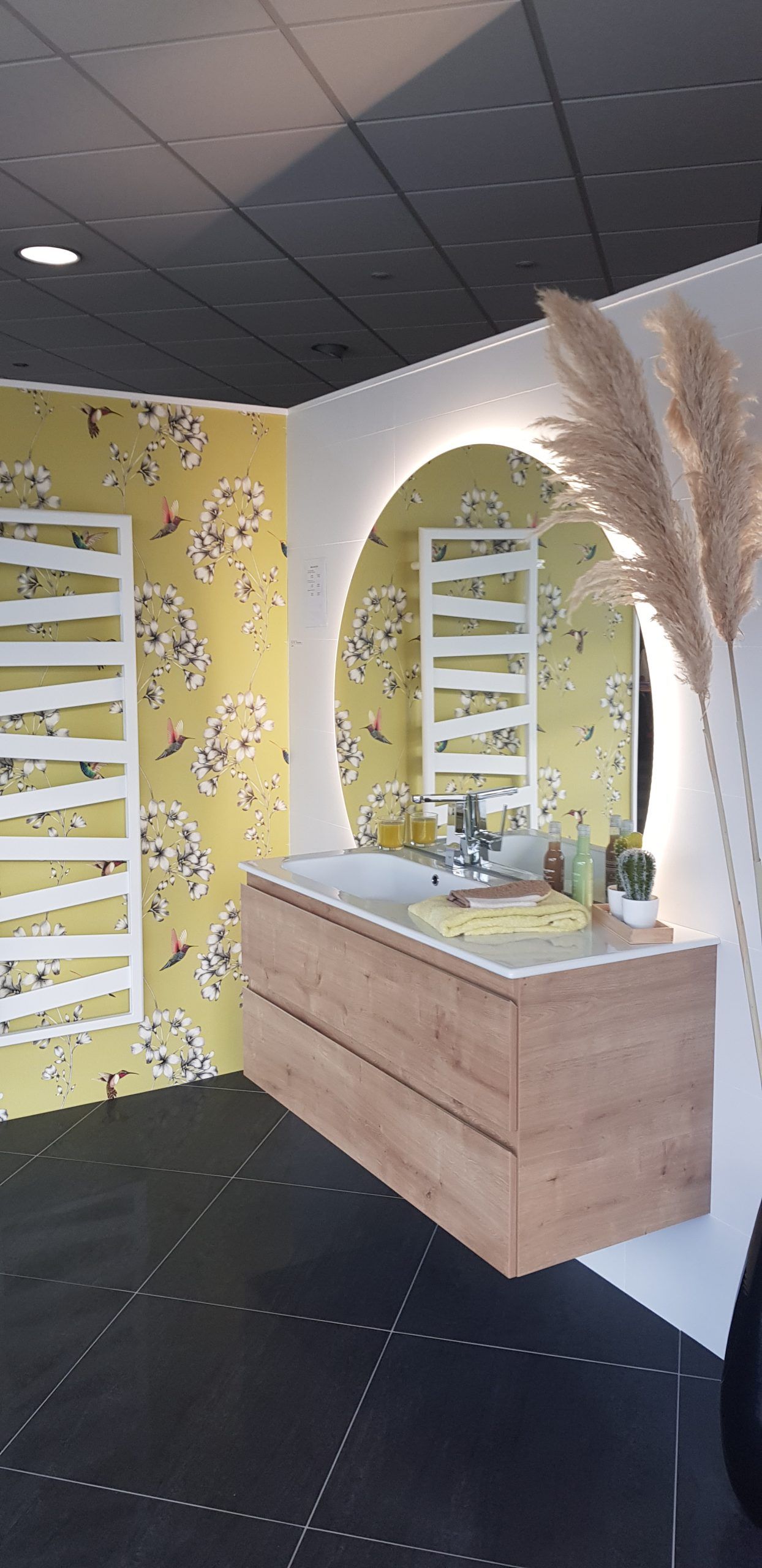 Présentoir de coiffeuse moderne avec miroir arqué, armoire en bois et murs à motifs floraux jaunes dans une salle d'exposition