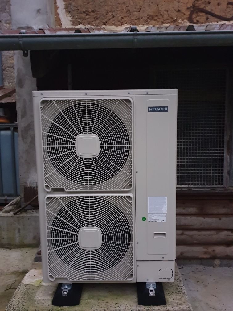 Unité de climatisation extérieure avec deux grands ventilateurs contre un mur