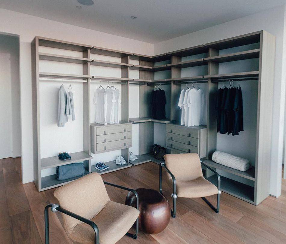 Dressing moderne avec étagères, penderie, portes miroir et deux chaises beiges sur parquet