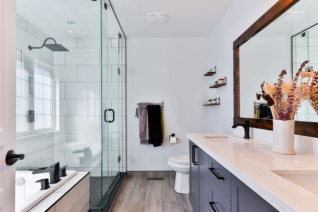 Salle de bains moderne avec douche en verre, double vasque, murs blancs et miroir encadré en bois