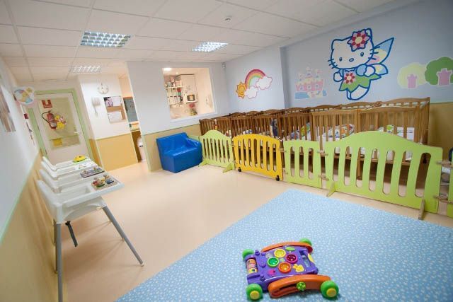 Una habitación con muchas cunas y juguetes.