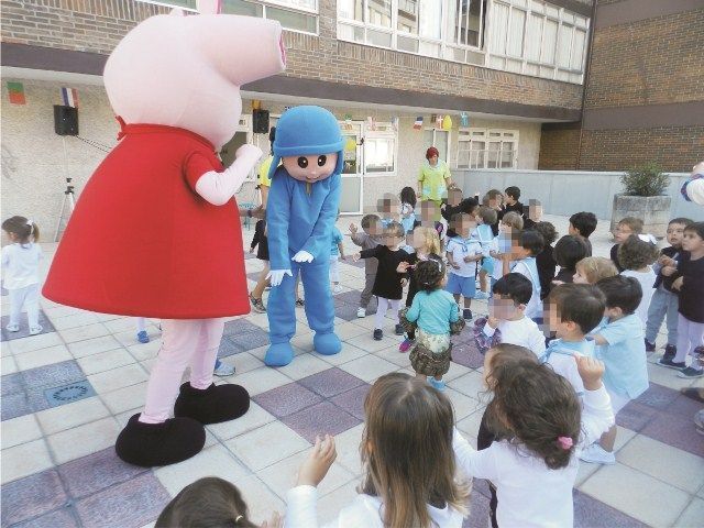 Las mascotas Peppa Pig y Pocoyo están paradas frente a un grupo de niños.
