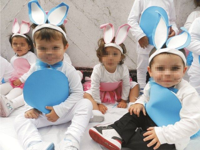 Un grupo de niños vestidos con disfraces de conejito están sentados en el suelo.