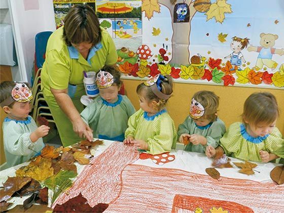 Un grupo de niños están sentados alrededor de una mesa con hojas sobre ella.