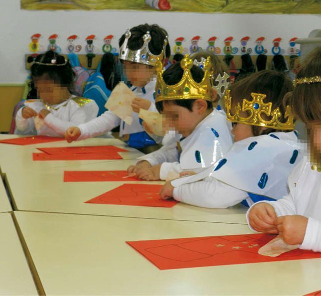 Un grupo de niños con coronas están sentados en mesas.