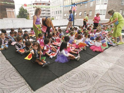 Un grupo de niños están sentados en una estera en el suelo.