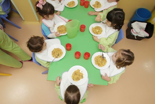Un grupo de niños están sentados en una mesa comiendo comida.