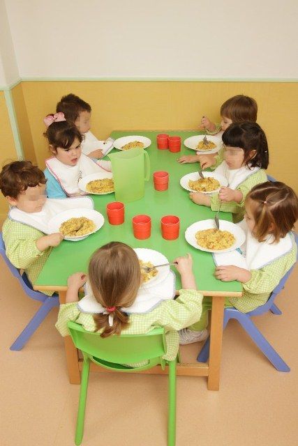 Un grupo de niños están sentados en una mesa comiendo comida.