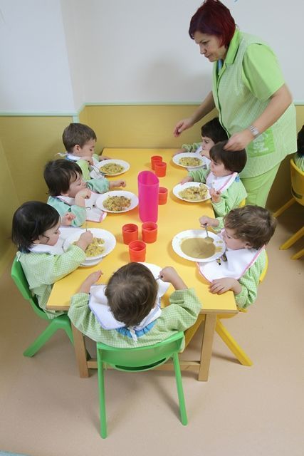 Un grupo de niños están sentados en una mesa comiendo comida.