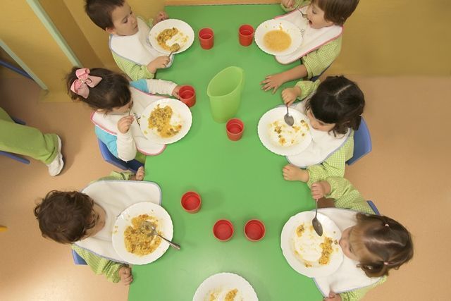Un grupo de niños están sentados en una mesa comiendo comida.