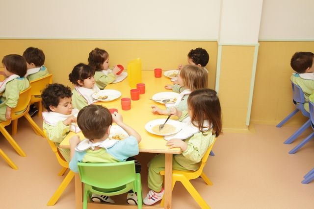 Un grupo de niños están sentados en una mesa comiendo comida.