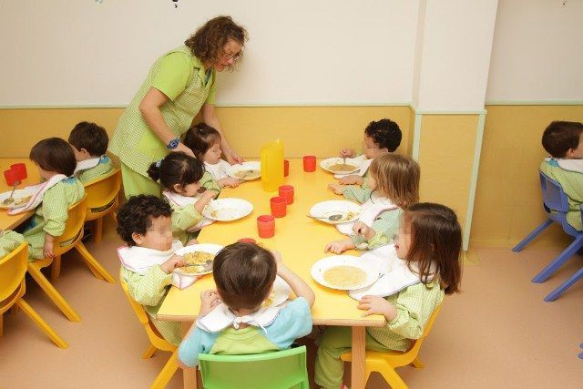 Un grupo de niños están sentados en una mesa comiendo comida.