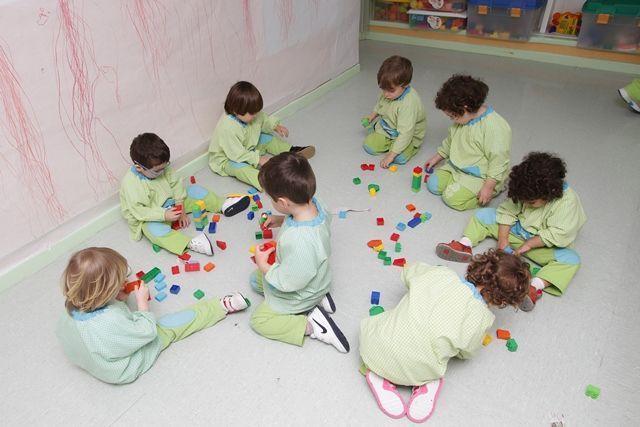 Un grupo de niños está sentado en el suelo jugando con bloques.