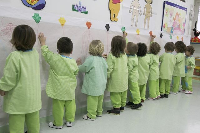 Un grupo de niños está parado frente a una pared y dibujando en ella.
