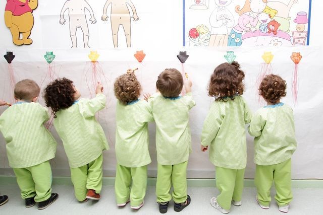 Un grupo de niños está parado frente a una pared con dibujos.