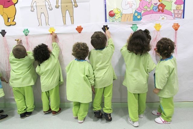 Un grupo de niños está parado frente a una pared con una imagen de Winnie the Pooh en ella.