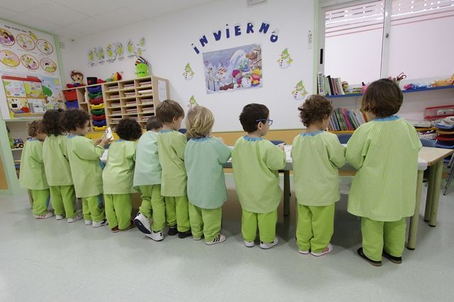 Un grupo de niños están de pie en un aula con una imagen en la pared que dice invierno.