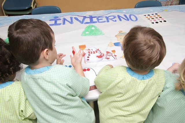 Un grupo de niños están sentados en una mesa con un cartel que dice invierno.