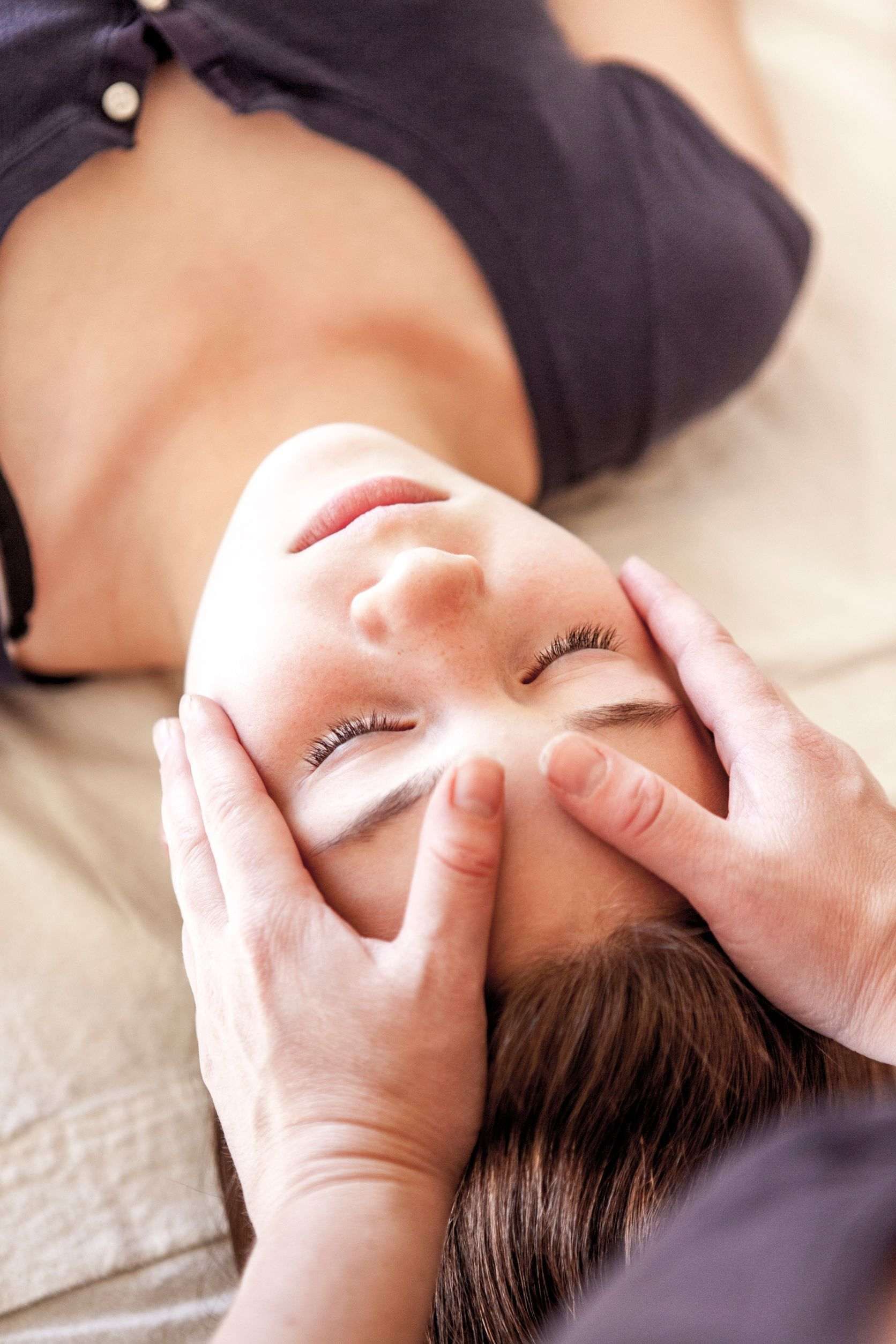 Una mujer está recibiendo un masaje en la cabeza con los ojos cerrados.