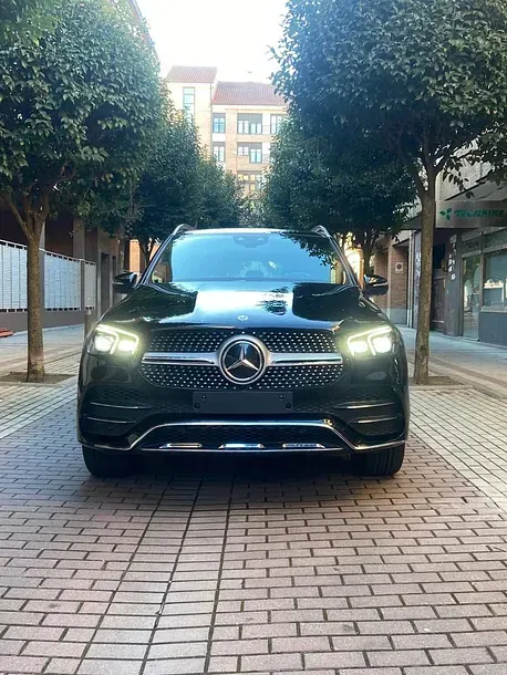 Un Mercedes Benz negro está estacionado en una acera de ladrillos.