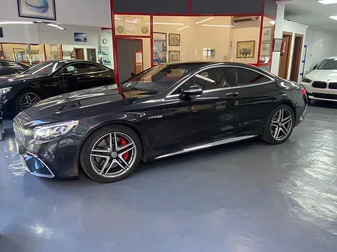 Un Mercedes Benz S63 AMG Coupé negro está estacionado en una sala de exposición.