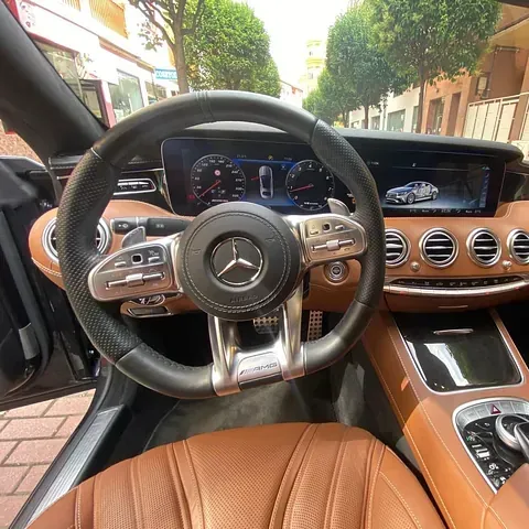 El interior de un mercedes benz con volante y tablero de instrumentos.