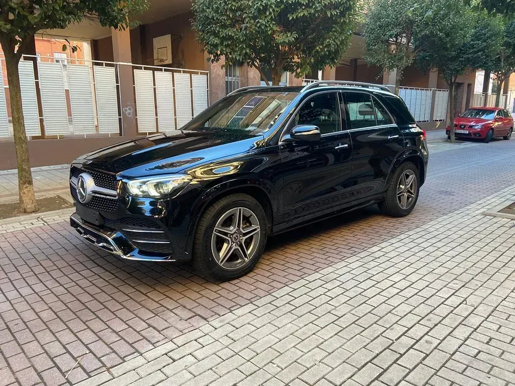 Una camioneta negra está estacionada en una acera de ladrillos frente a un edificio.