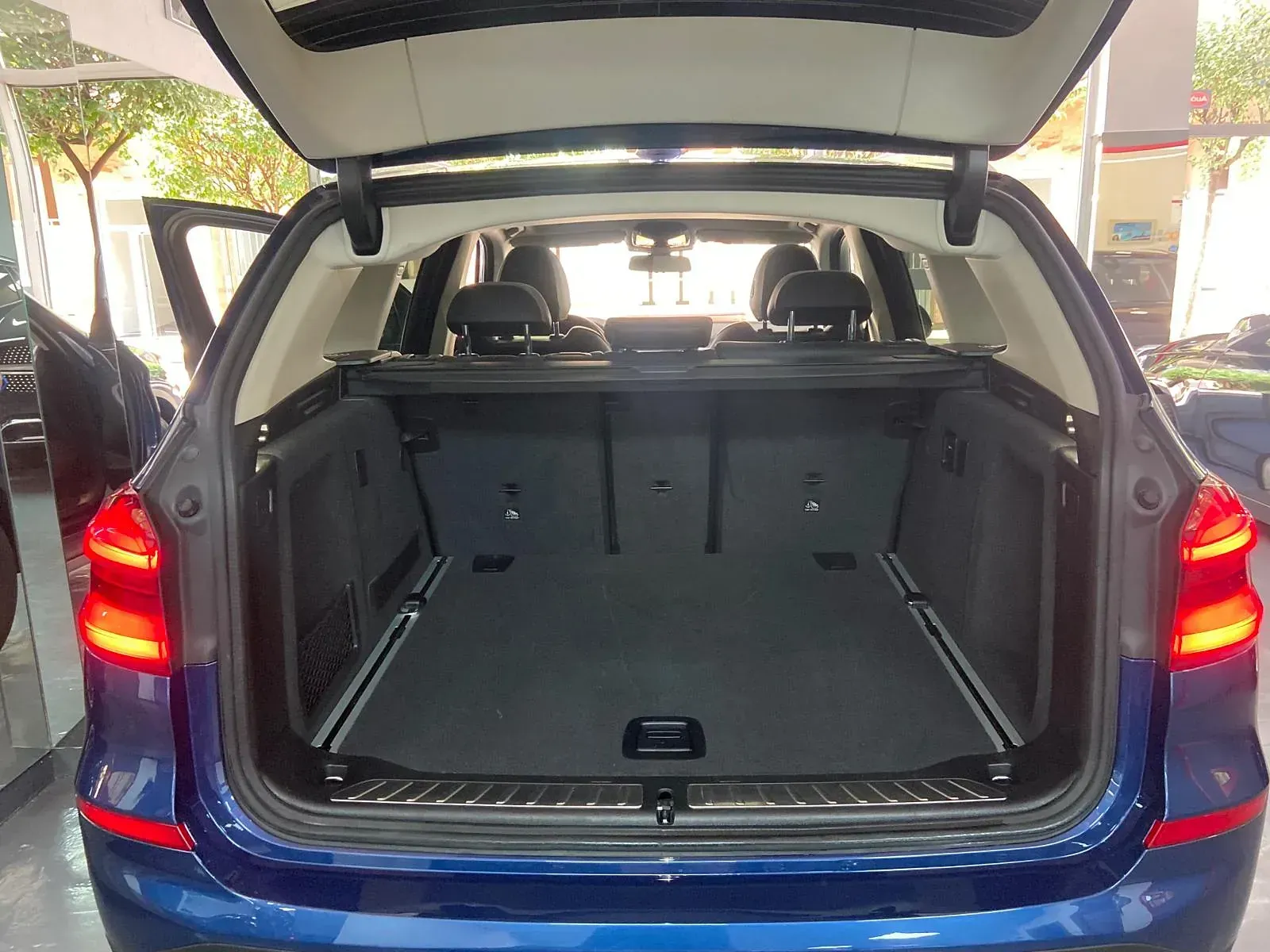 El maletero de un BMW X3 azul está abierto y vacío.