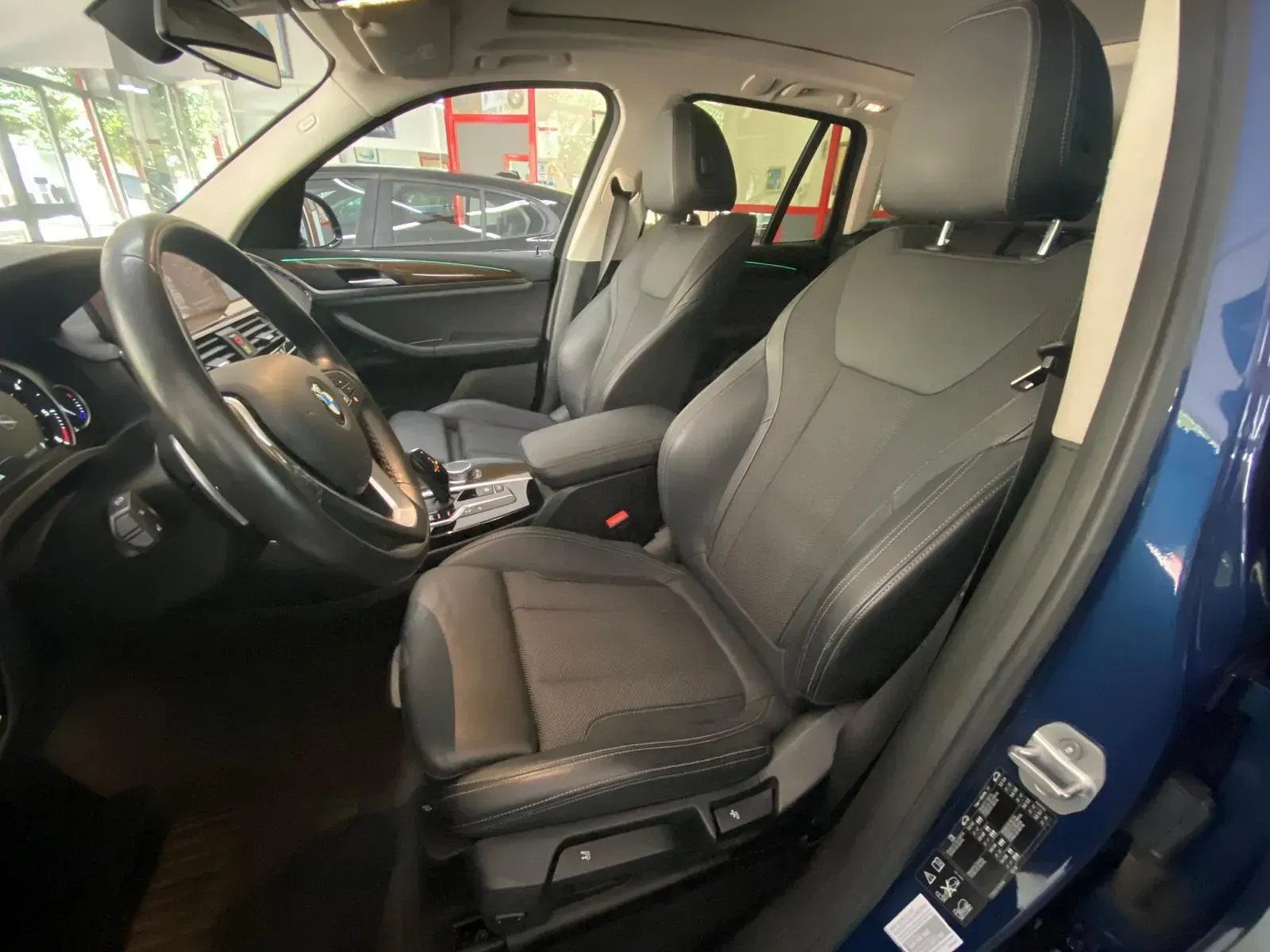 El interior de un coche azul con asientos negros y un volante.