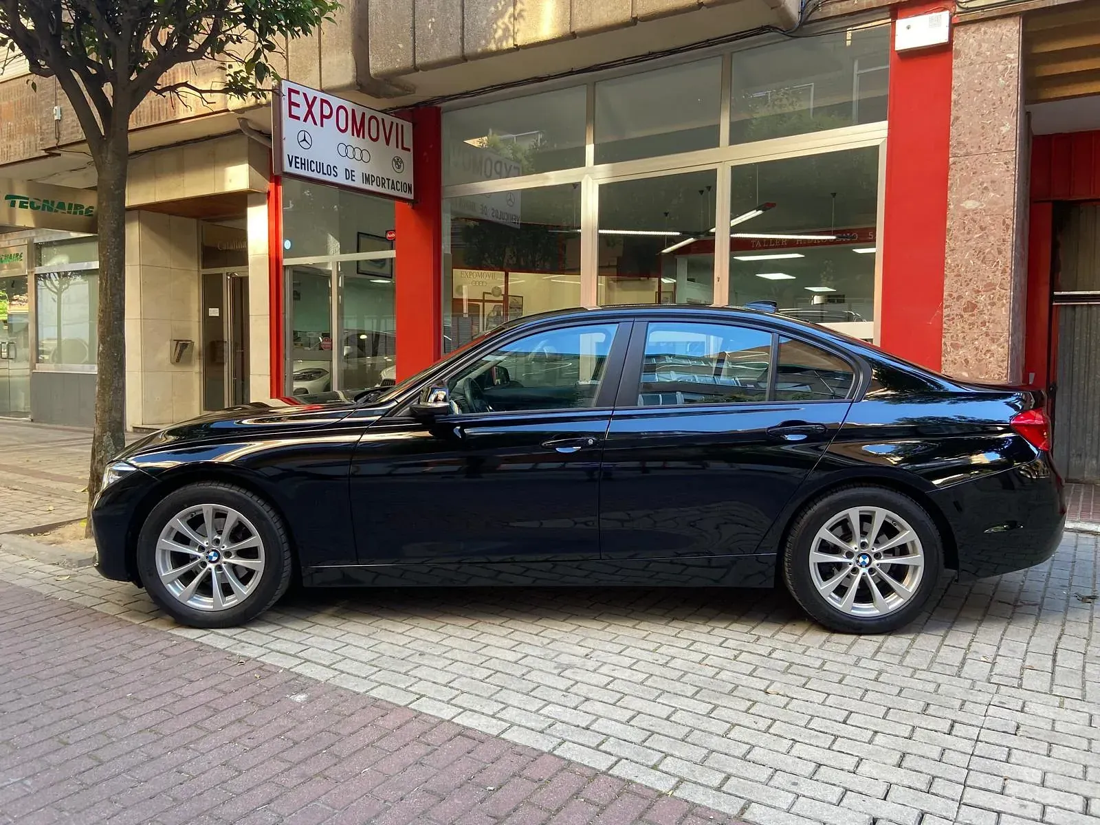 Un coche negro está aparcado delante de un edificio.