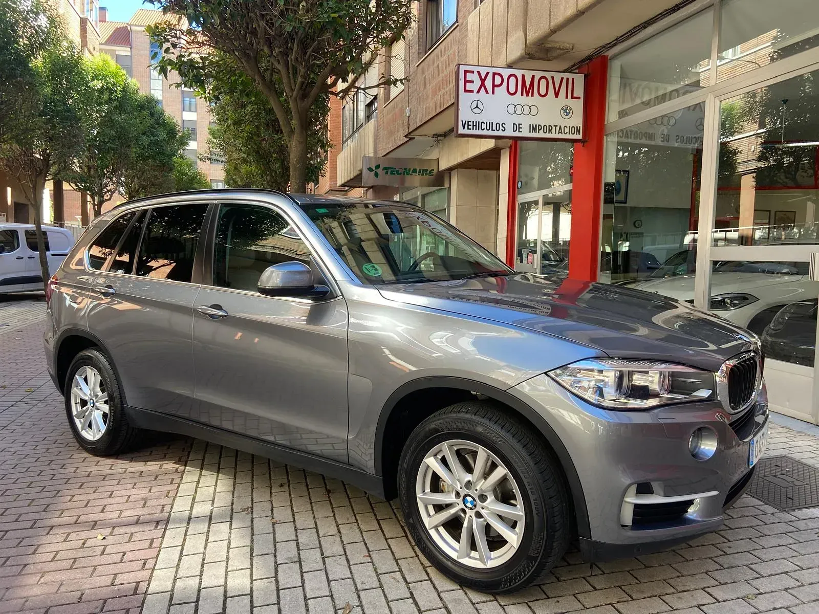 Un BMW X5 está estacionado frente a un concesionario de automóviles.
