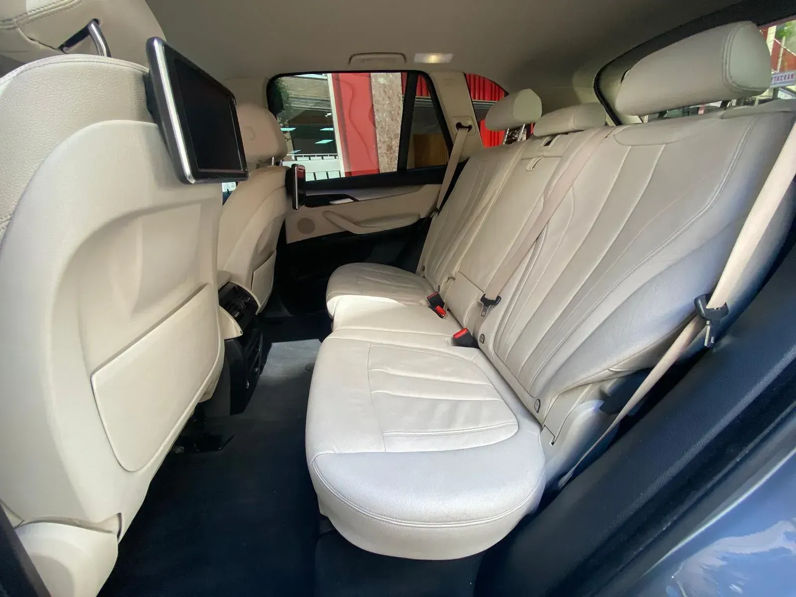 El asiento trasero de un BMW X5 con asientos de cuero blanco.