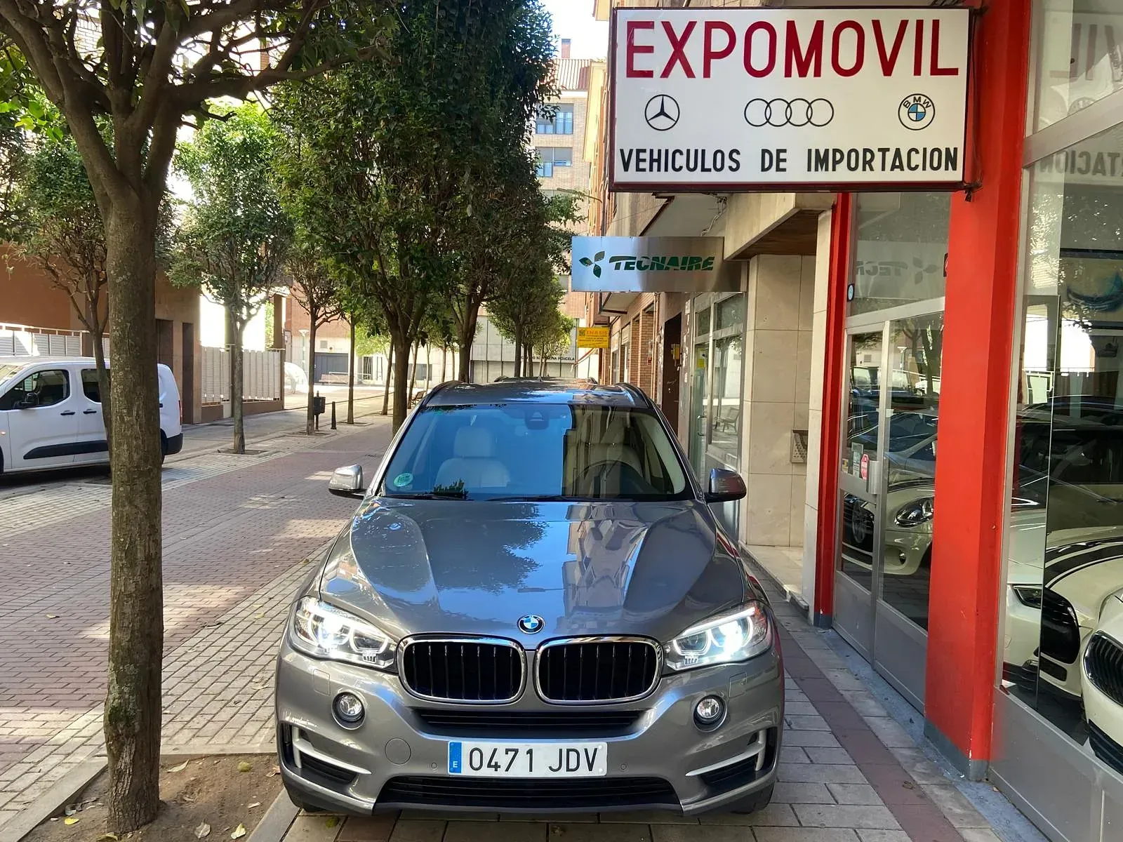 Un BMW X6 está estacionado frente a un concesionario de automóviles.