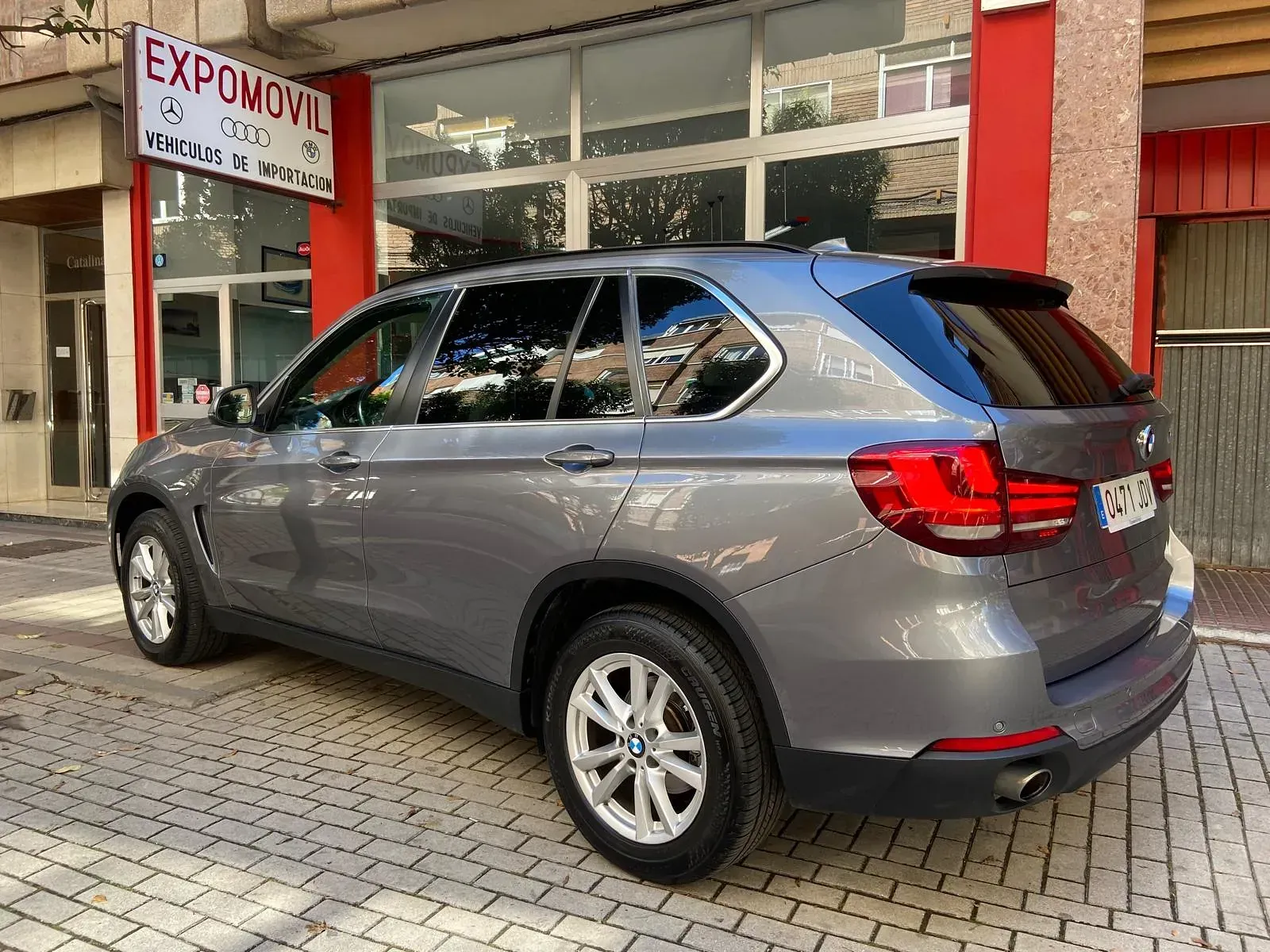 Un BMW X5 está estacionado frente a un concesionario de automóviles.