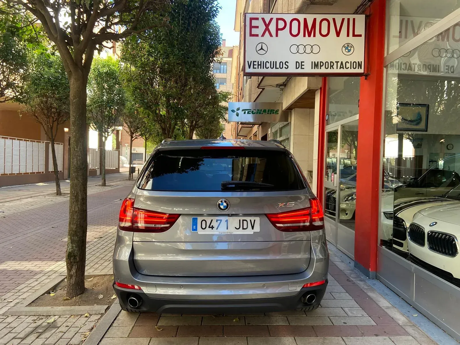 Un BMW está aparcado delante de un concesionario de coches.