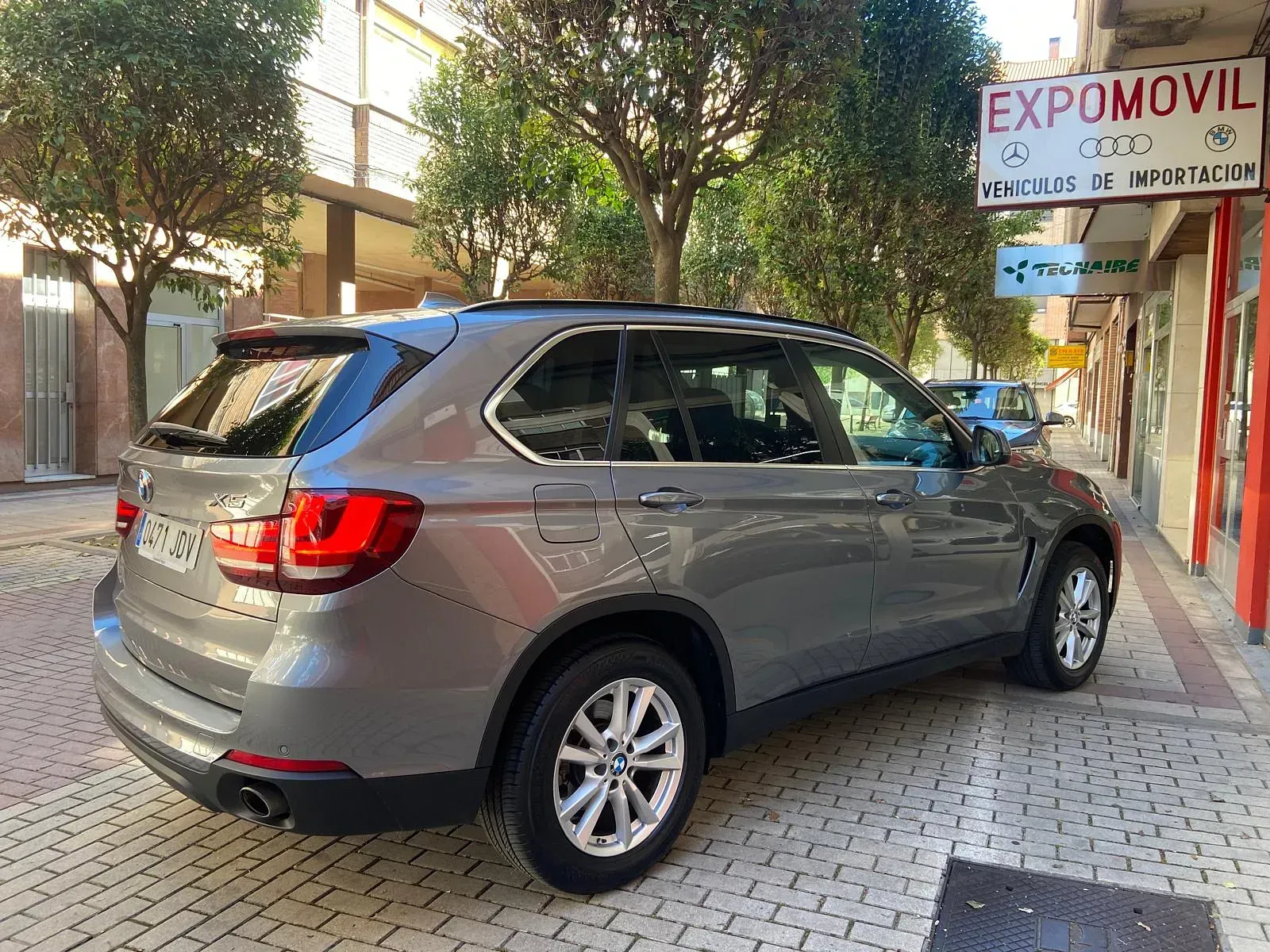 Un BMW X5 está estacionado al costado de la carretera frente a un edificio.