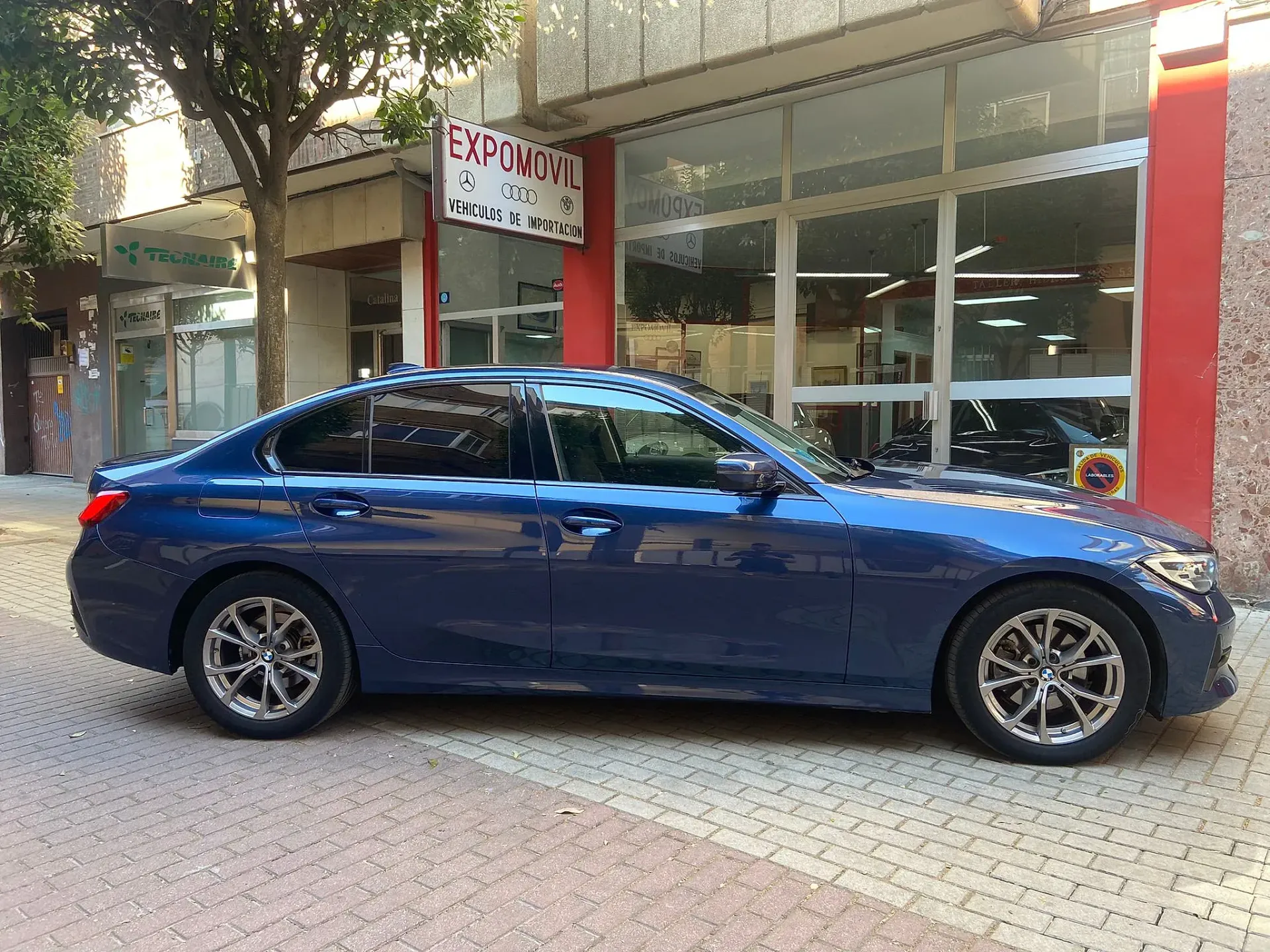 Un coche azul está aparcado delante de un edificio.