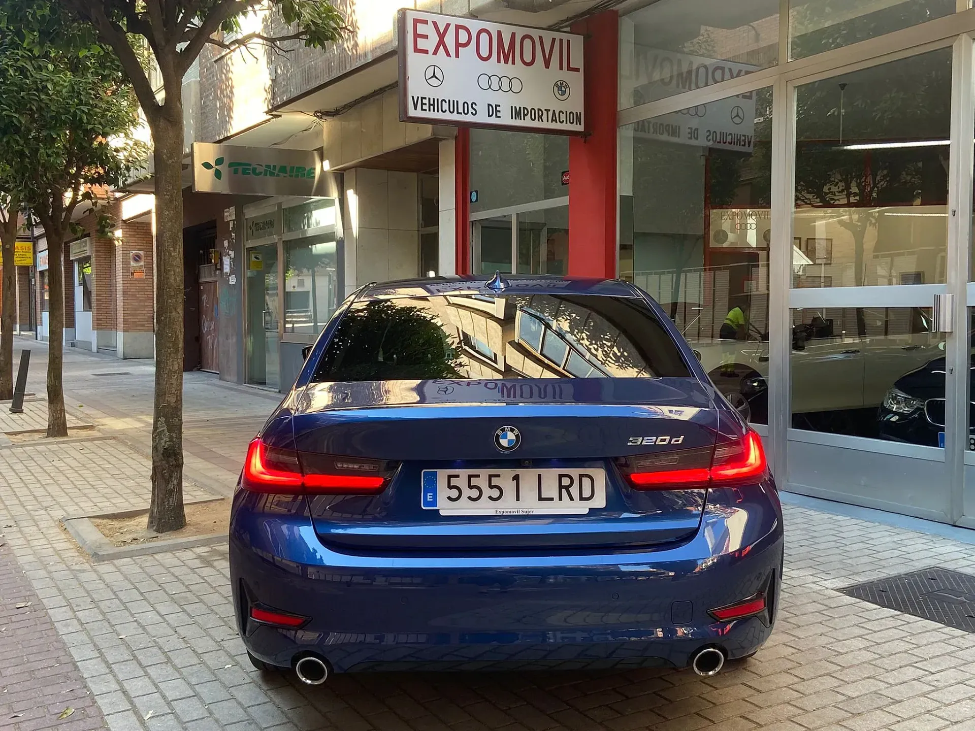 Un coche azul está aparcado delante de un cartel que dice expomovil