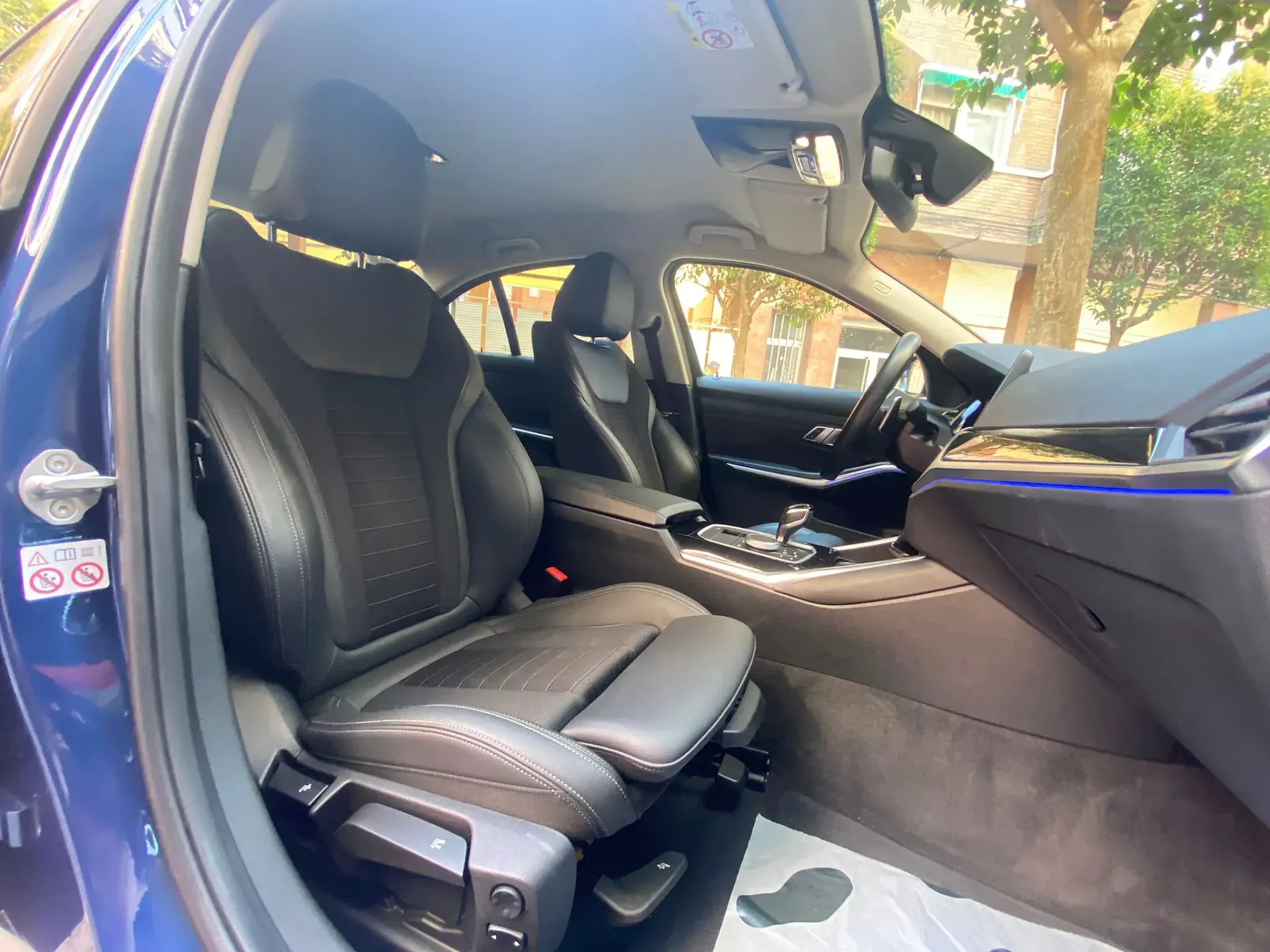 El interior de un coche azul con asientos de cuero negro y un volante.