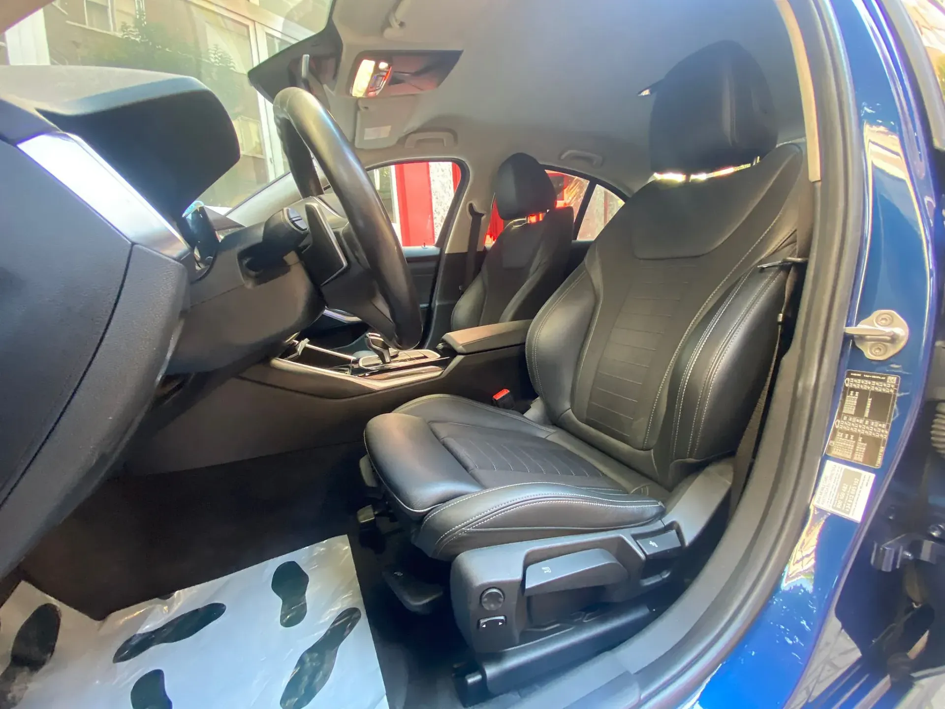 El interior de un coche azul con asientos de cuero negro y un volante.