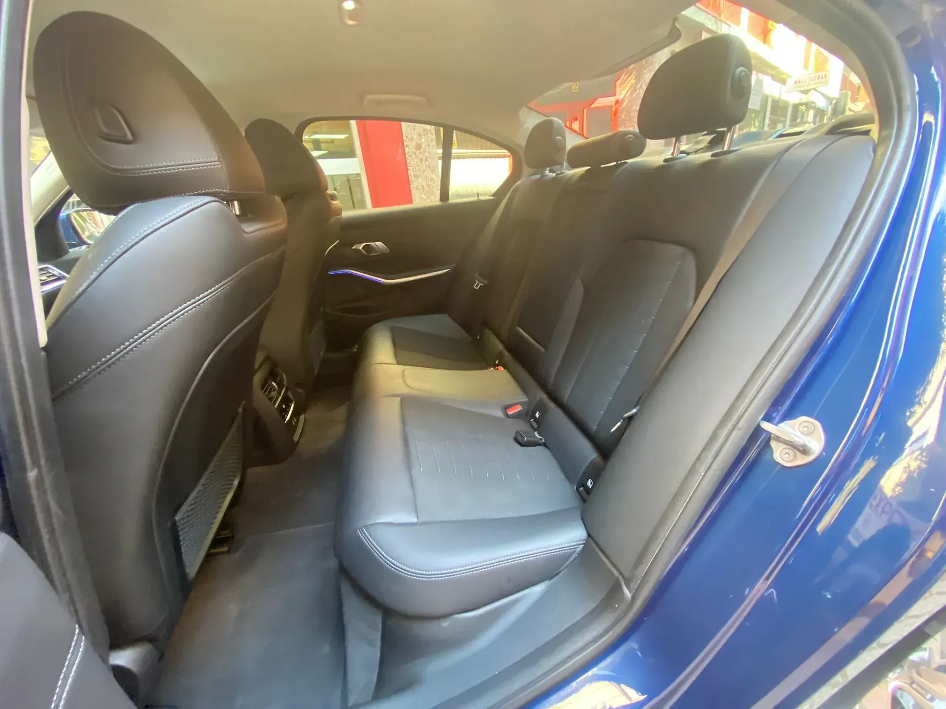 El asiento trasero de un coche azul con asientos de cuero negro.