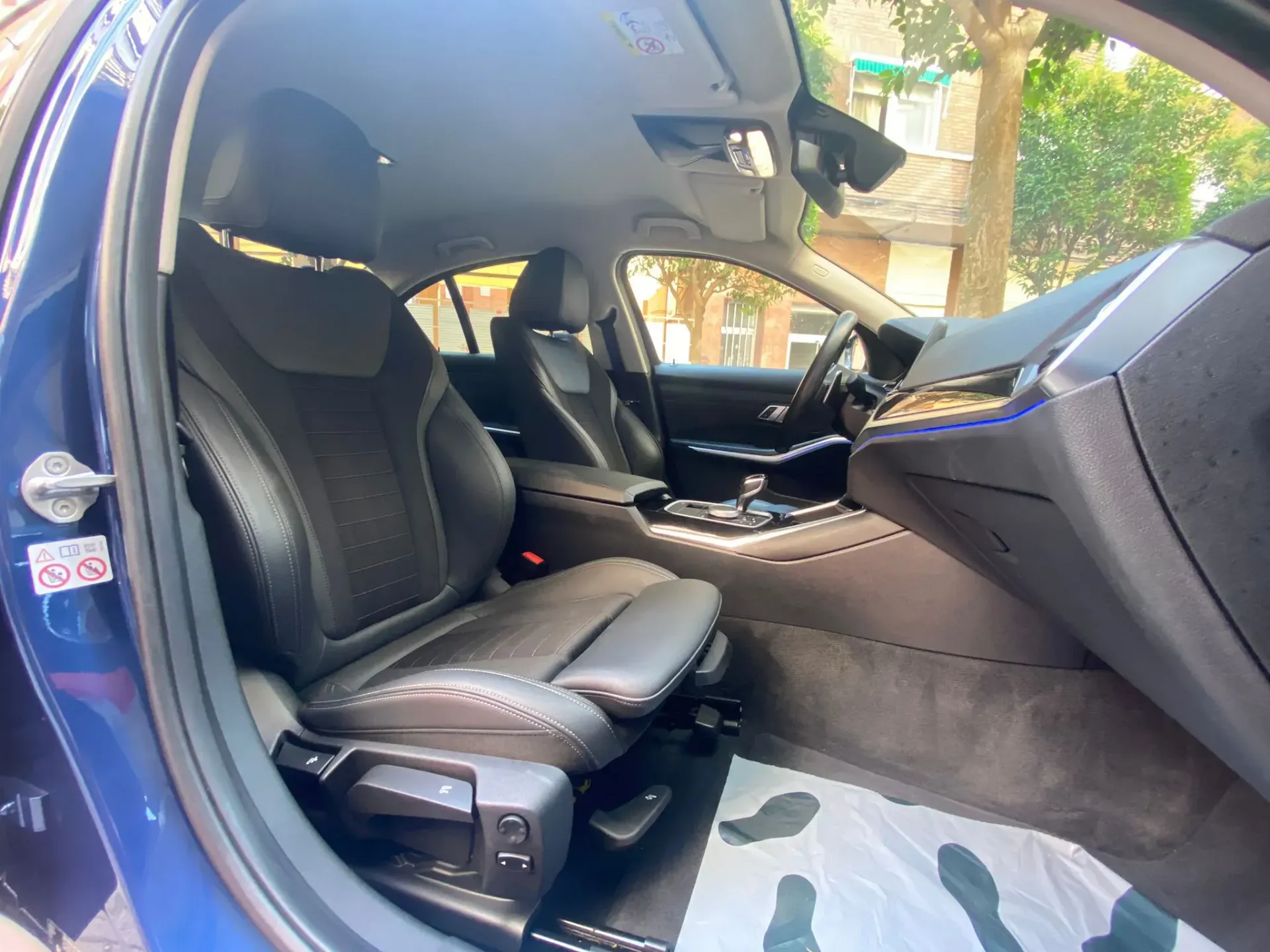 El interior de un coche azul con asientos de cuero negro.