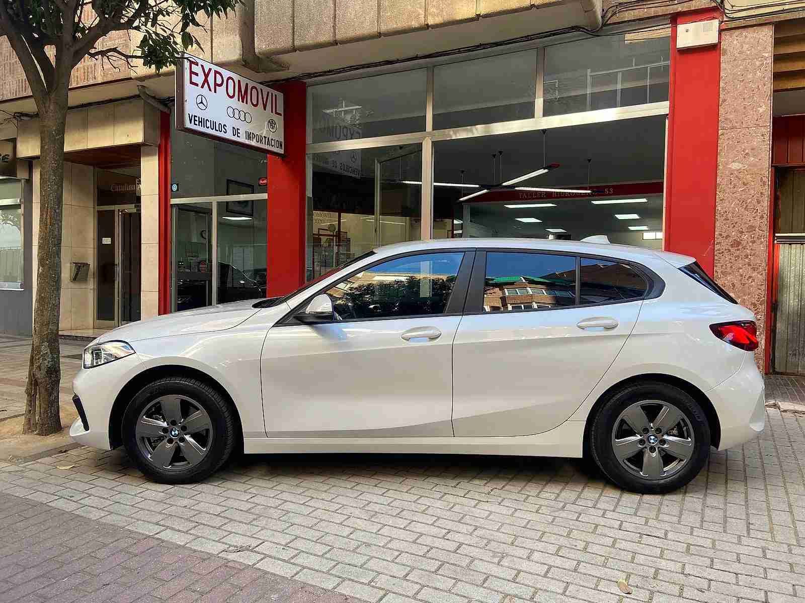 Un coche blanco está aparcado delante de un concesionario de automóviles.