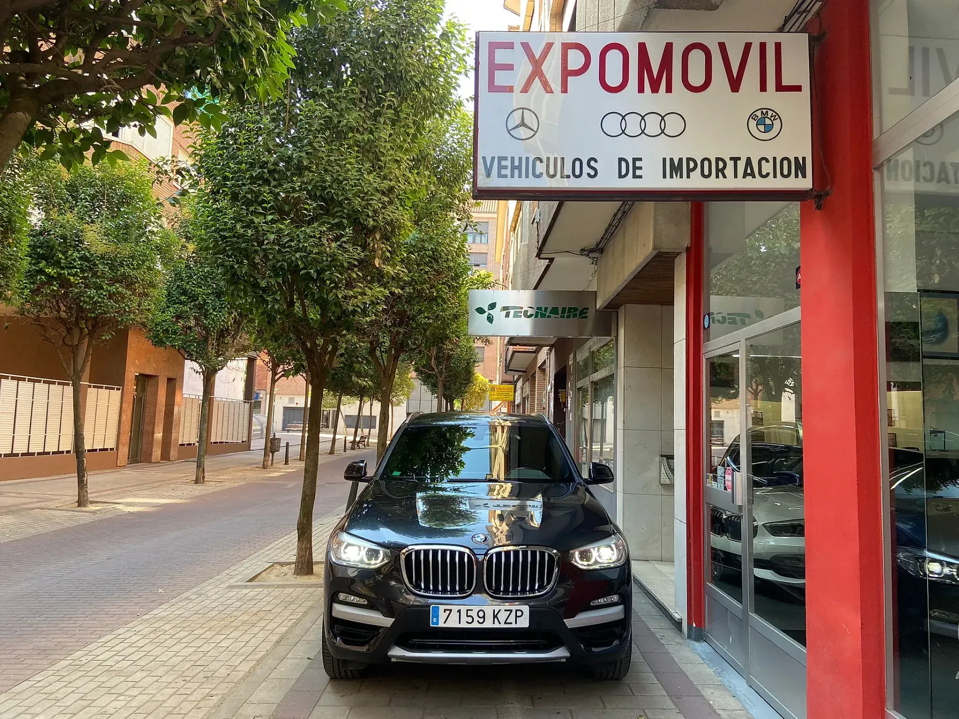 Un coche negro está aparcado delante de un concesionario de automóviles.