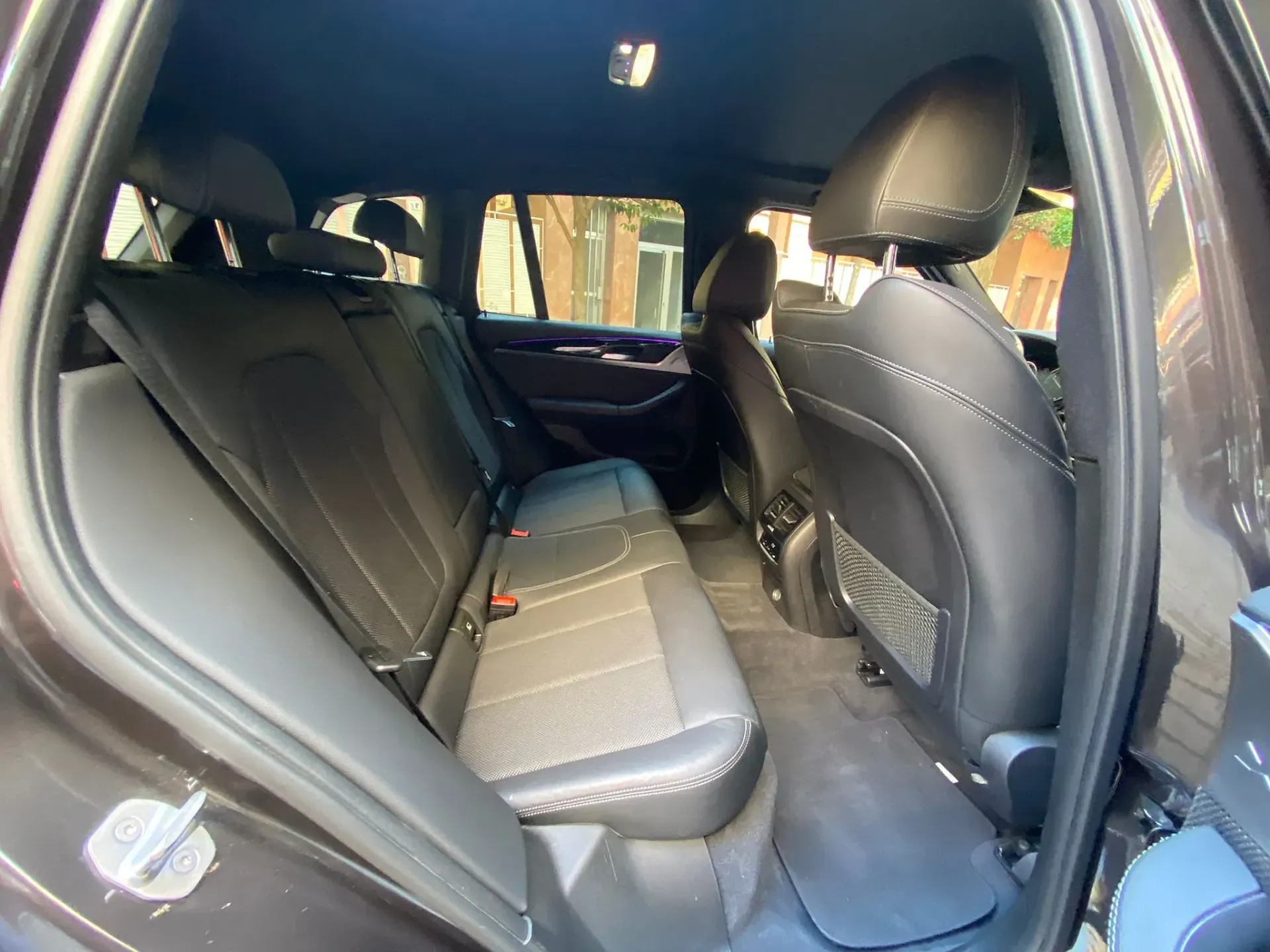 Se muestra el asiento trasero de un BMW X3 negro.