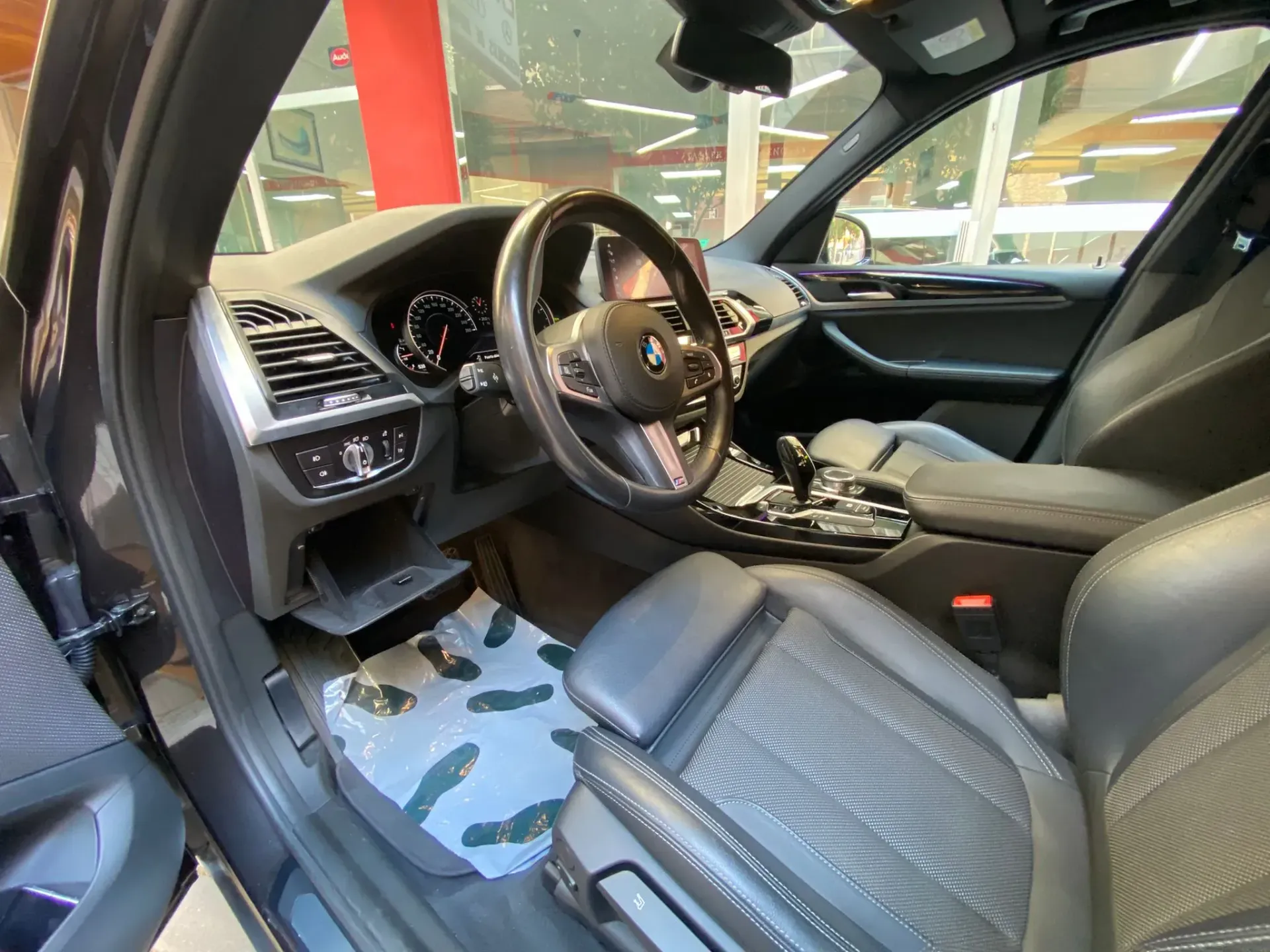 Se muestra el interior de un BMW X3 con la puerta abierta.