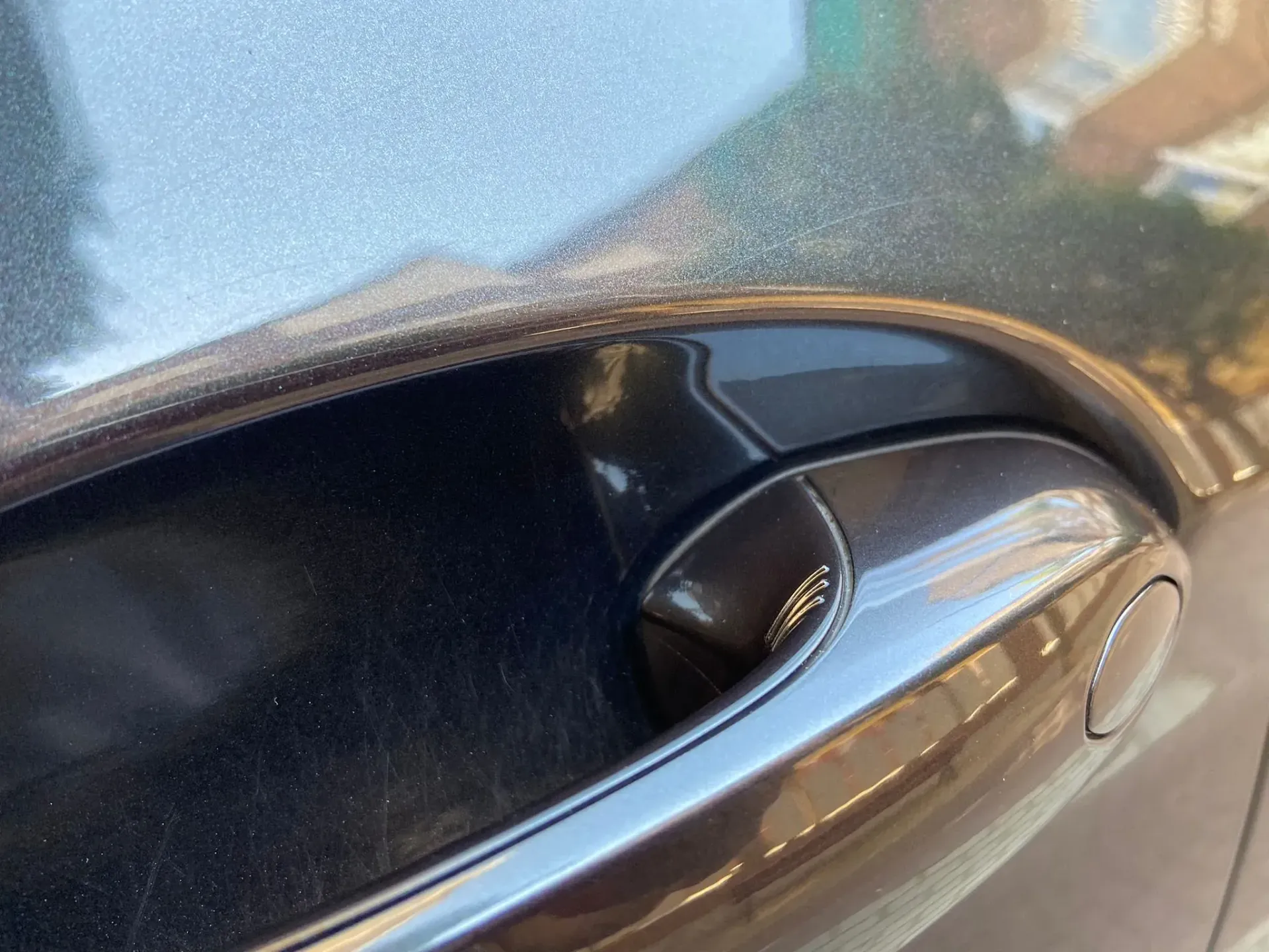 Un primer plano de la manija de la puerta de un automóvil negro.