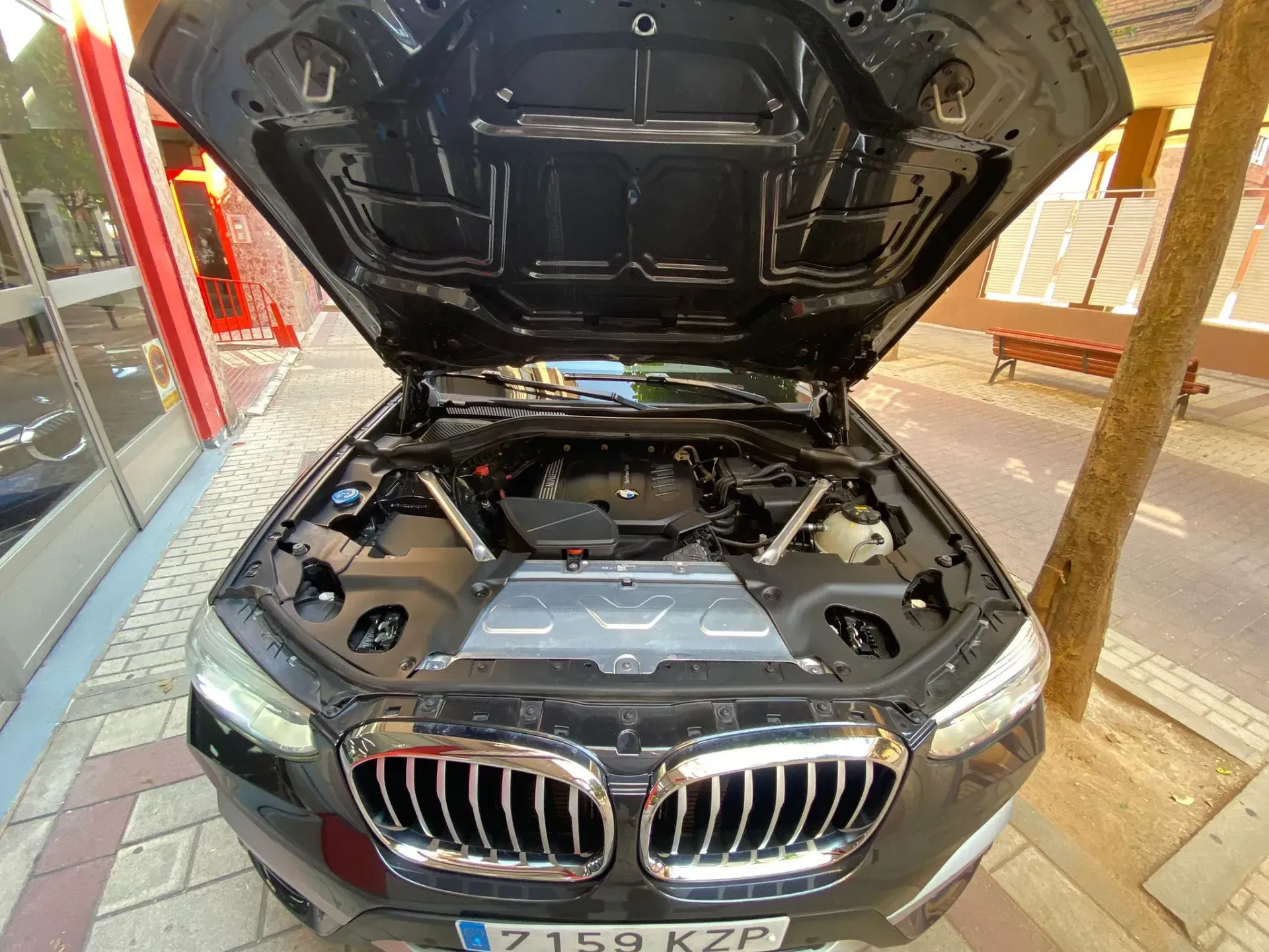 El capó de un BMW está abierto y muestra el motor.